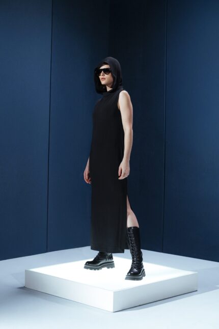 Vestido longo em jersey preto com capuz e fendas laterais. Silhueta reta com toque urbano e sofisticado. Conforto e presença em um só gesto
