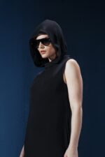 Vestido longo em jersey preto com capuz e fendas laterais. Silhueta reta com toque urbano e sofisticado. Conforto e presença em um só gesto