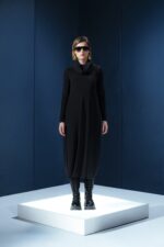 Vestido midi preto em jersey com mangas longas, gola drapeada e amarrações laterais. Silhueta ajustável com elegância e conforto.
