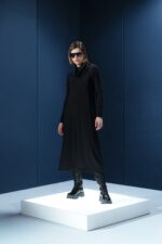 Vestido midi preto em jersey com mangas longas, gola drapeada e amarrações laterais. Silhueta ajustável com elegância e conforto.