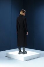 Vestido midi preto em jersey com mangas longas, gola drapeada e amarrações laterais. Silhueta ajustável com elegância e conforto.