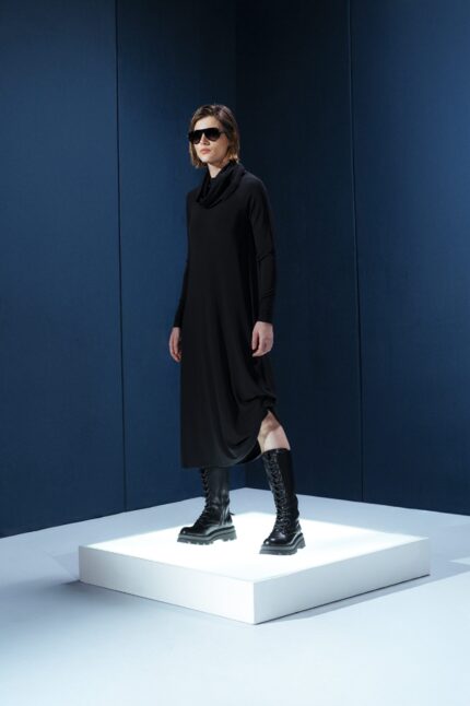 Vestido midi preto em jersey com mangas longas, gola drapeada e amarrações laterais. Silhueta ajustável com elegância e conforto.