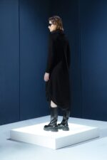 Vestido midi preto em jersey com mangas longas, gola drapeada e amarrações laterais. Silhueta ajustável com elegância e conforto.