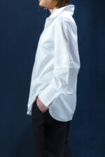 Camisa branca de tricoline com recorte estratégico no cotovelo. Silhueta reta com refinamento contemporâneo e caimento sofisticado.