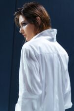 Camisa branca de tricoline com recorte estratégico no cotovelo. Silhueta reta com refinamento contemporâneo e caimento sofisticado.