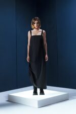 Vestido preto em lã fria com alças ajustáveis nas costas e argolas metálicas laterais que permitem franzir a peça. Design versátil e sofisticado.