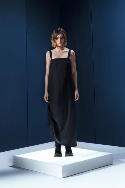 Vestido preto em lã fria com alças ajustáveis nas costas e argolas metálicas laterais que permitem franzir a peça. Design versátil e sofisticado.