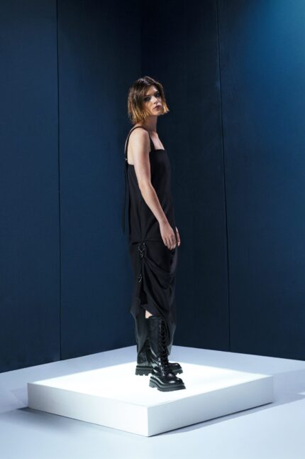 Vestido preto em lã fria com alças ajustáveis nas costas e argolas metálicas laterais que permitem franzir a peça. Design versátil e sofisticado.