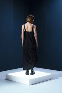 Vestido preto em lã fria com alças ajustáveis nas costas e argolas metálicas laterais que permitem franzir a peça. Design versátil e sofisticado.