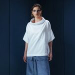 Camisa de tricoline com gola ampla e recortes diagonais. Uma peça contemporânea com inspiração arquitetônica e caimento estruturado.