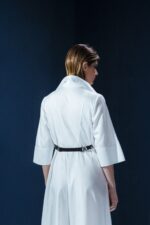 Vestido de tricoline branco com mangas 3/4 e detalhe de couro nas costas. Modelagem elegante com cintura marcada e recortes estruturados.