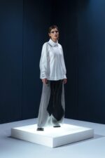 Camisa em tricoline branca com argola de metal no punho. Silhueta clássica com detalhe contemporâneo e toque de alfaiataria minimalista.