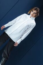 Camisa branca em tricoline com gola alta e abotoamento embutido. Estrutura limpa e elegante com caimento preciso e sofisticação minimalista.