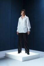 Camisa branca de tricoline com recorte estratégico no cotovelo. Silhueta reta com refinamento contemporâneo e caimento sofisticado.