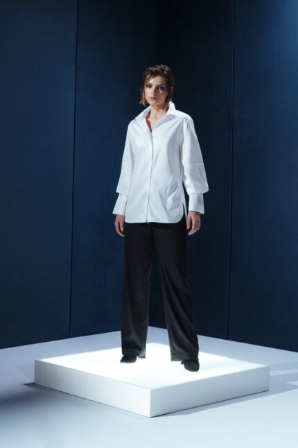 Camisa branca de tricoline com recorte estratégico no cotovelo. Silhueta reta com refinamento contemporâneo e caimento sofisticado.